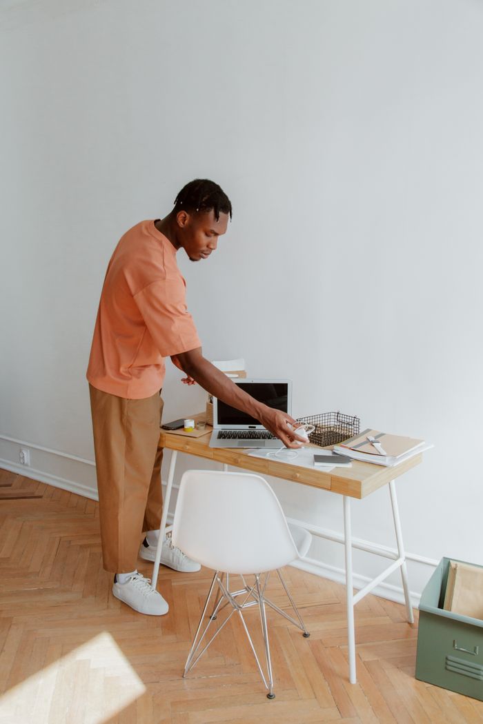 services-01 A man standing at a desk organizing papers and electronic devices in a modern office setting.